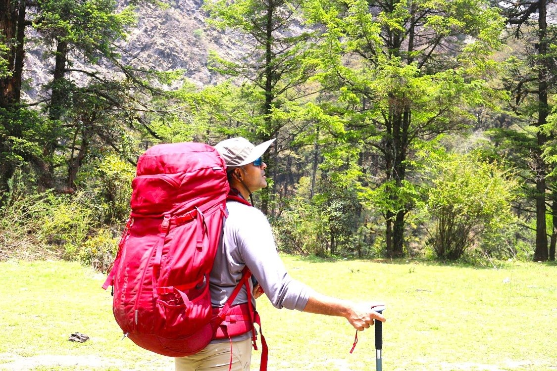 Trekker hiking uphill on a rugged Langtang Valley trail while preparing for a challenging mountain trek.