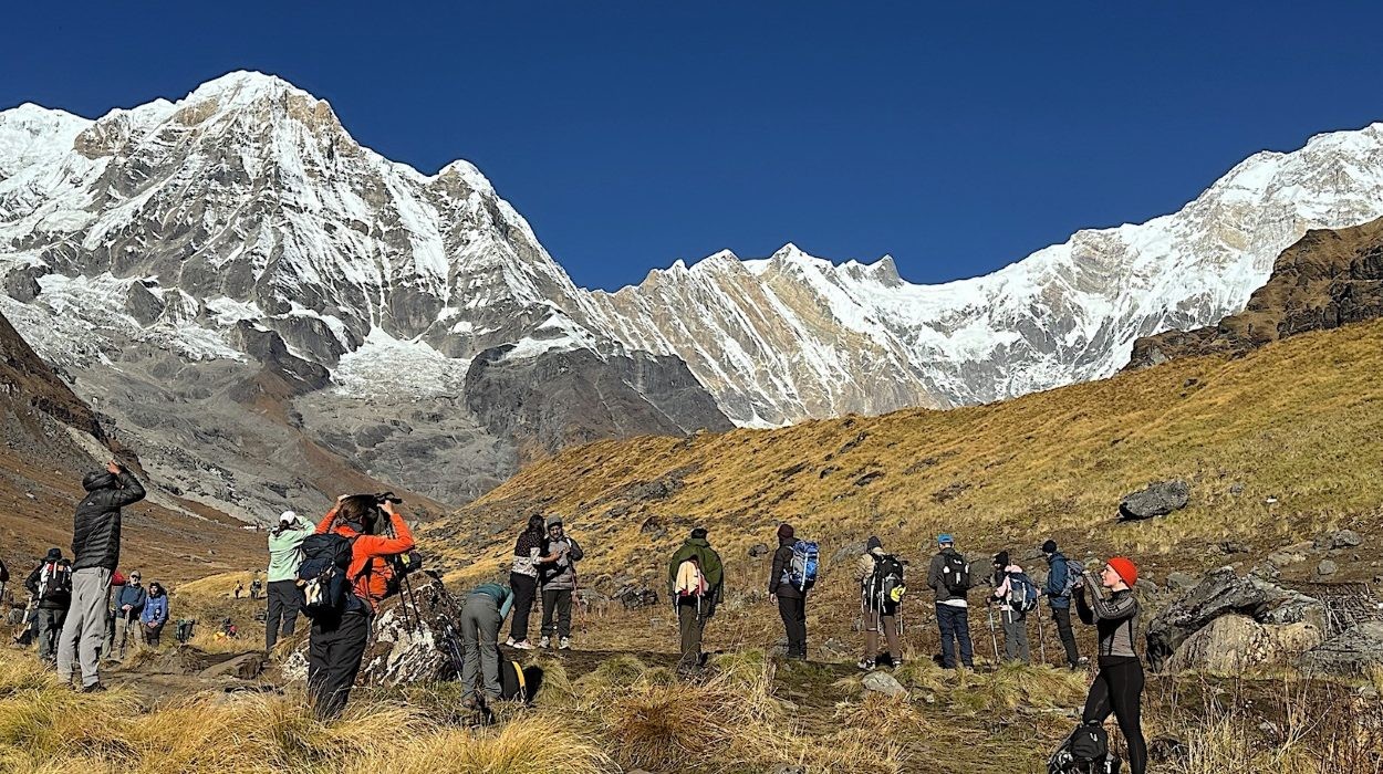 Trekkers heading toward Annapurna Base Camp along a scenic mountain trail with spectacular views of snow-covered Himalayan peaks.