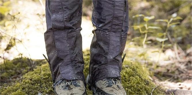 Trekking scene showing muddy Himalayan trail conditions with trekkers wearing waterproof trousers and trail gaiters to protect from rain, mud, and debris in Nepal.
