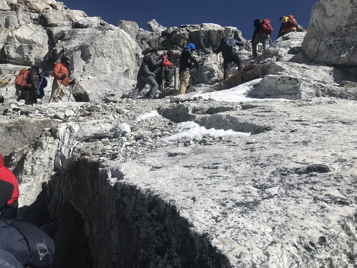  "Trekkers ascending the steep rocky and snowy slopes of Cho La Pass (5,420 m) in the Everest region, highlighting the challenging high-altitude Himalayan terrain" 