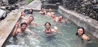 Natural hot spring pool in Nepal surrounded by rocks, forested hills, and Himalayan trekking landscapes where trekkers relax after mountain journeys.