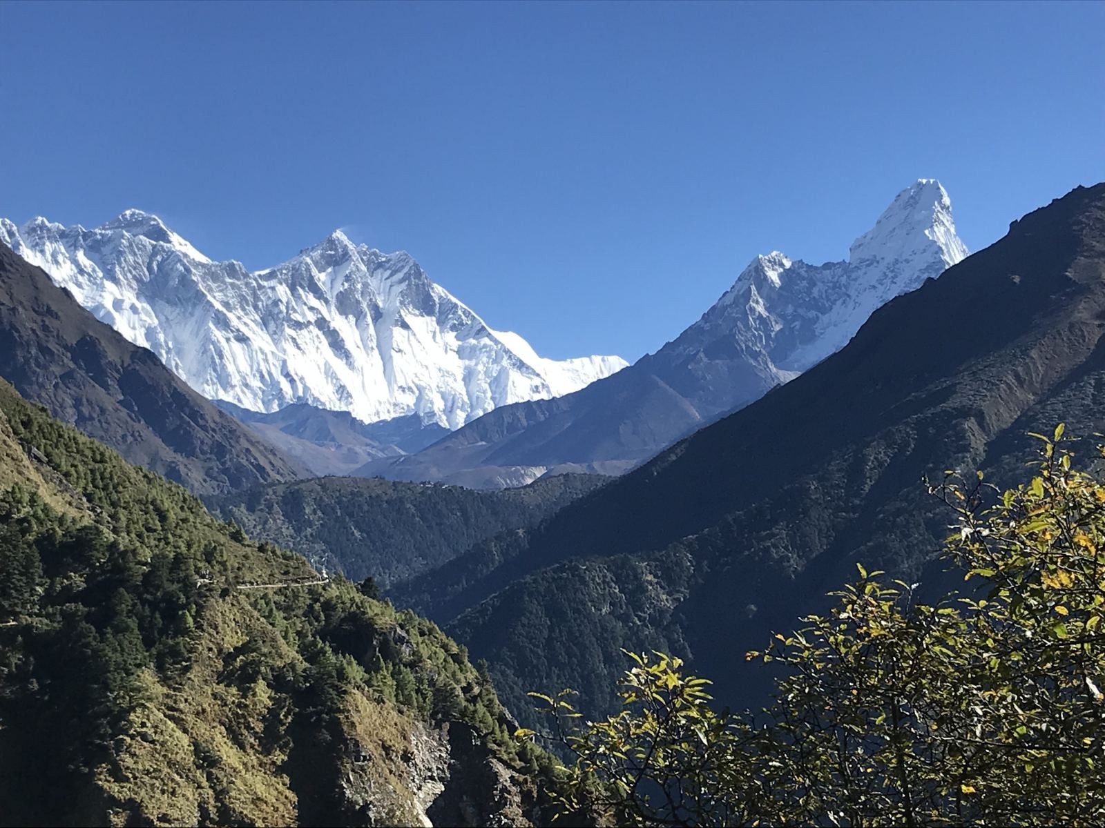 Scenic trekking trail in the Everest region with breathtaking views of Mount Everest, Lhotse, Ama Dablam, and lush Himalayan valleys under a crystal-clear blue sky.