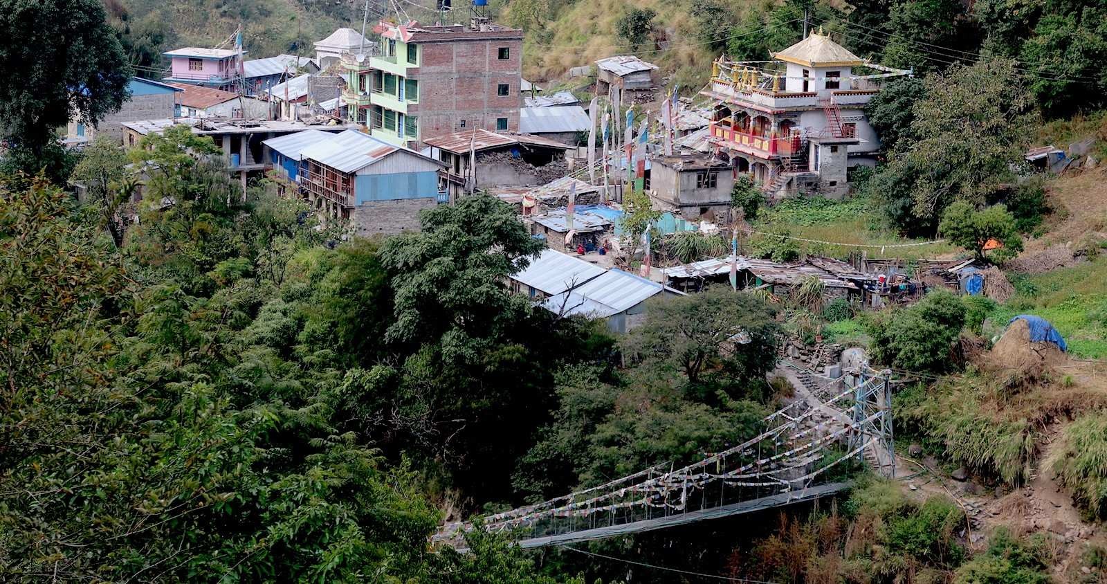Syabrubesi village in October with lush green hills, the Bhote Koshi River, traditional houses, and clear blue skies at the gateway to the Langtang Valley Trek in Nepal.
