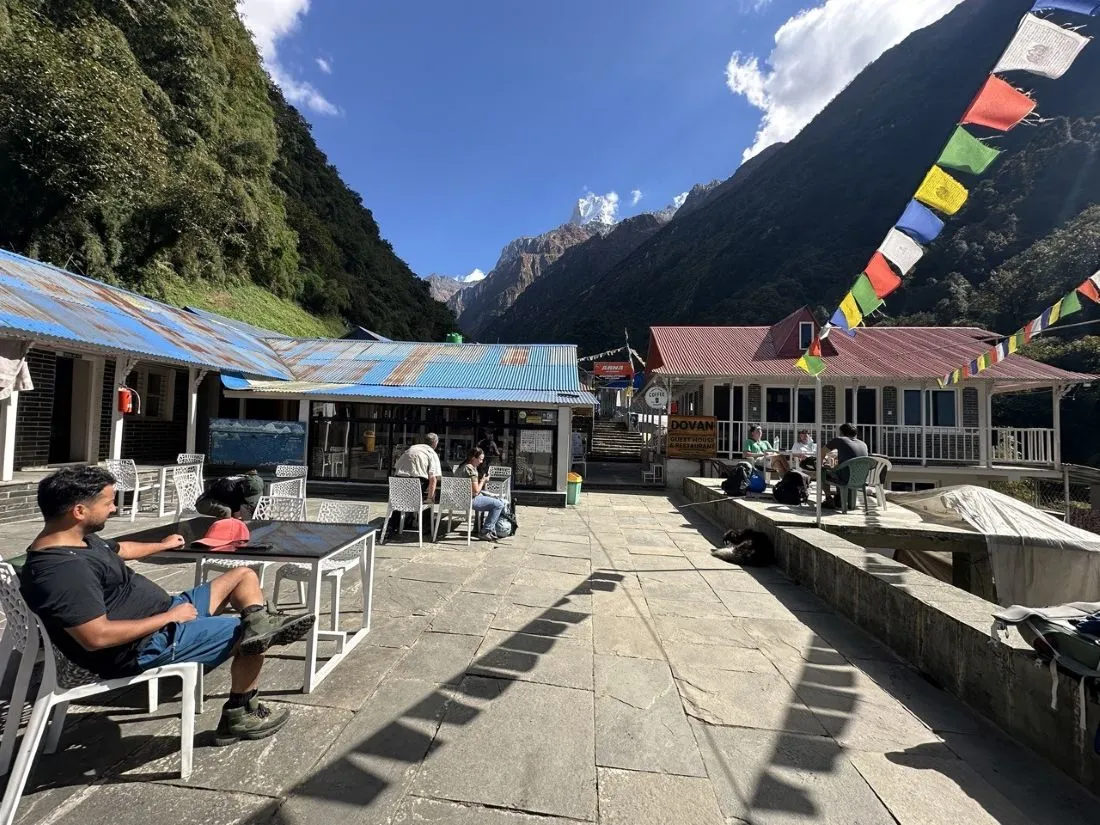 .Traditional teahouse accommodation on the Annapurna Base Camp Trek featuring cozy wooden rooms, twin beds, warm dining hall with a fireplace, mountain lodges, and stunning views of the Annapurna Himalayas.
