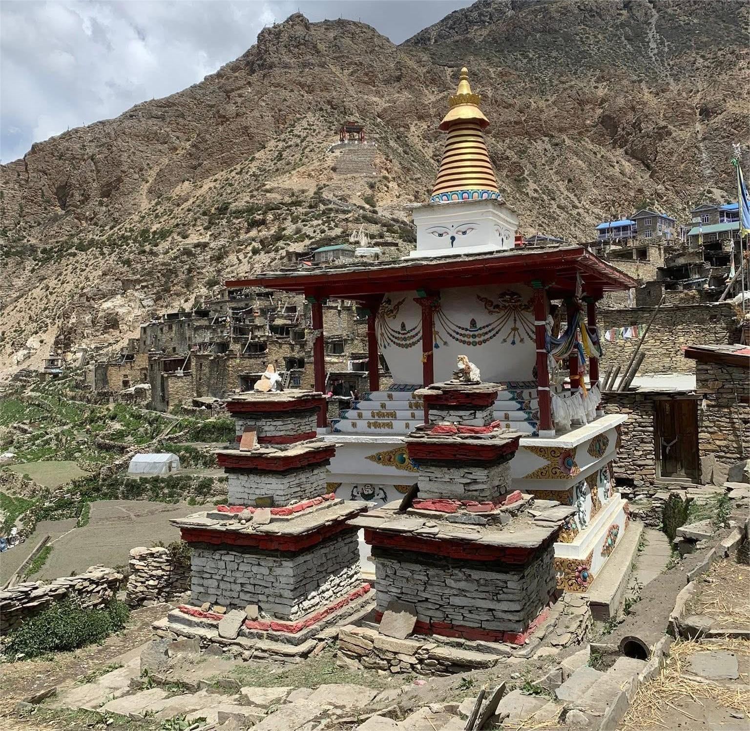 Buddhist stupa in Nepal Himalayas along trekking trail in Nar Phu or Manaslu region showing prayer flags, stone architecture and mountain landscape