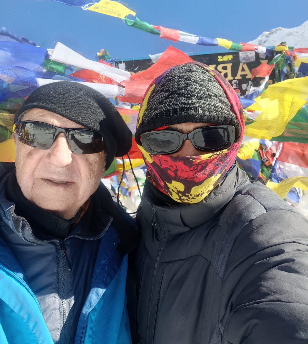 Trekker wearing a warm down jacket in the cold high-altitude environment of the Manaslu Circuit Trek with snow-capped Himalayan peaks in the background.