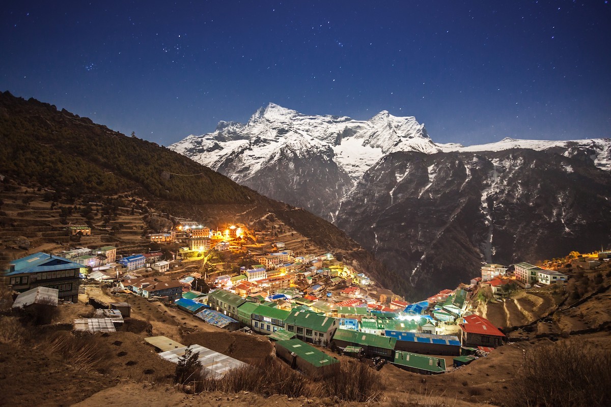 "Namche Bazaar illuminated under moonlight at night with Kongde Ri towering above the Sherpa town in Nepal's Everest region." 