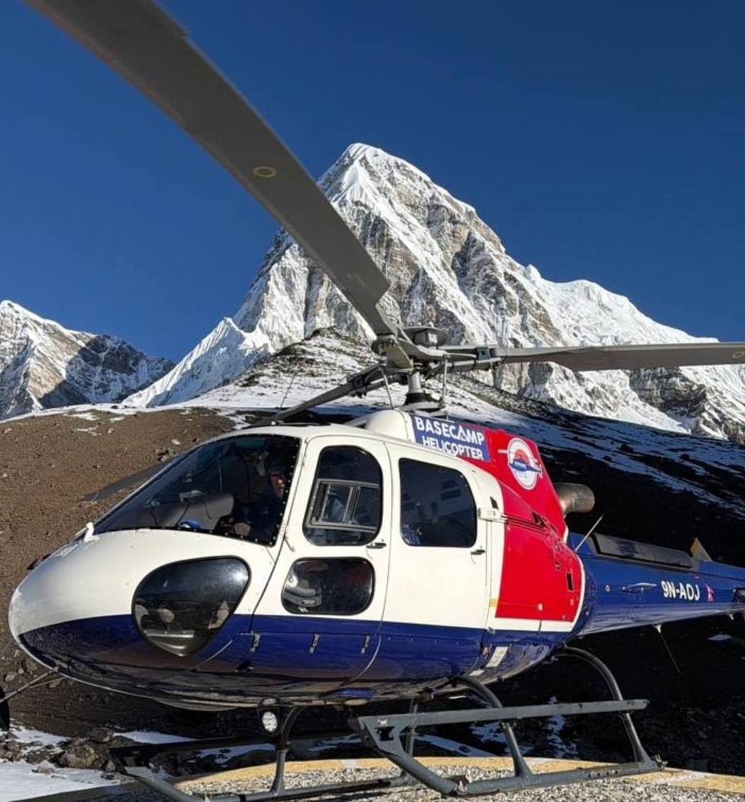 Helicopter landing at Gorak Shep to pick up passengers, with Mount Pumori and the rugged Himalayan landscape towering above the Everest Base Camp Trek route.
