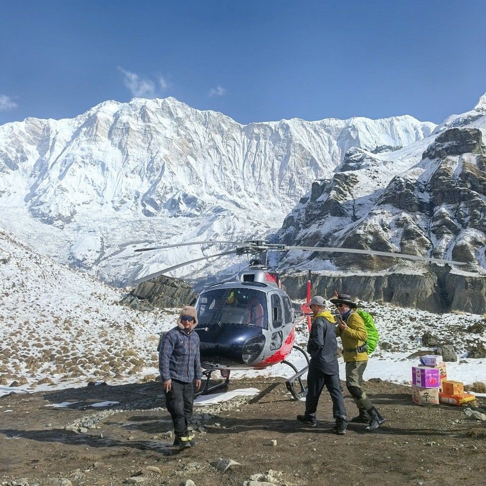 Helicopter landing at Annapurna Base Camp surrounded by snow-covered Himalayan peaks in the Annapurna Sanctuary.