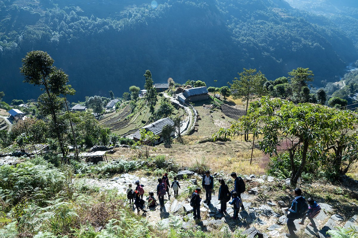 Trekkers walking through terraced fields and traditional villages on the final trail from Ghandruk to Nayapul and Birethanti in Nepal's Annapurna region.