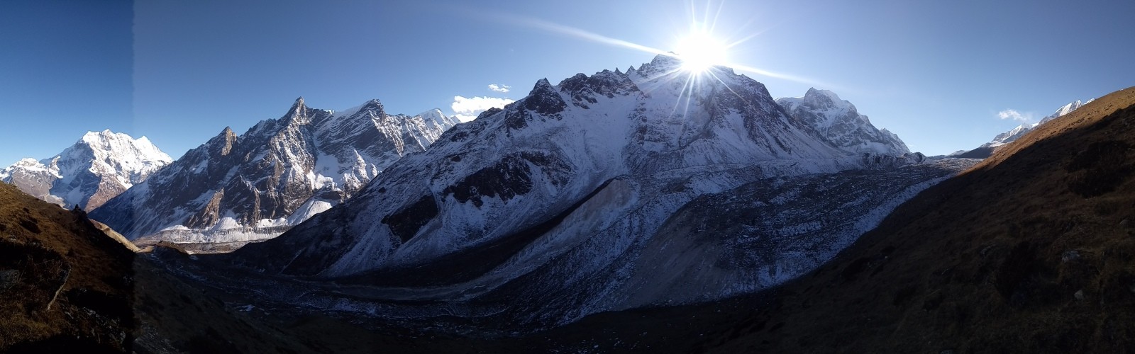 Sunrise over snow-covered Himalayan peaks on the trail to Larke Pass, with warm morning light illuminating the rugged alpine landscape.