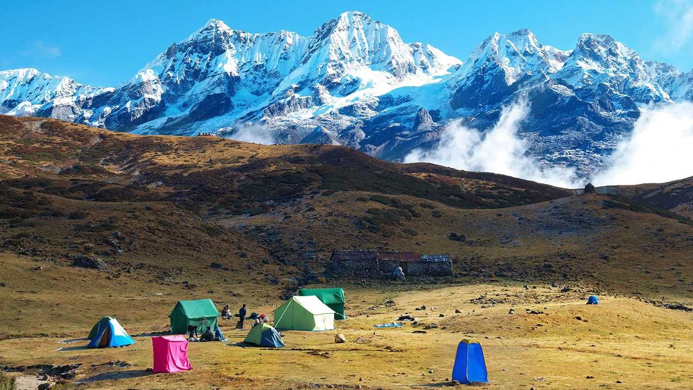 Trekkers hiking toward Kanchenjunga Base Camp through remote Himalayan terrain with towering snow-capped peaks.