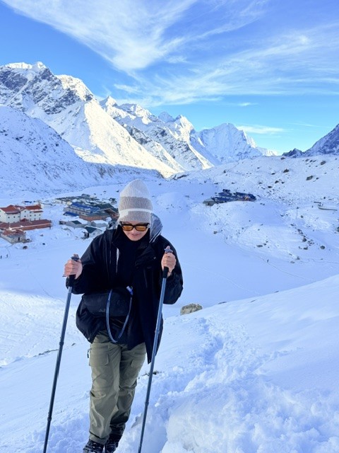 Trekker hiking from Gorak Shep to Kala Patthar through fresh snow with Mount Everest and the surrounding Himalayan peaks in winter.