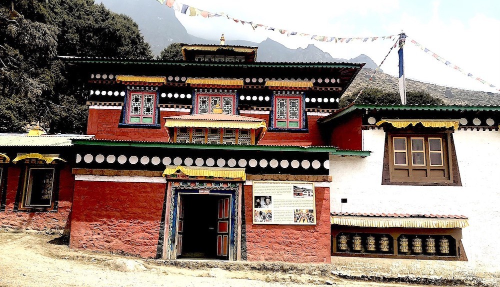 "Khumjung Monastery in the Everest region featuring traditional Sherpa architecture, colorful Buddhist prayer flags, sacred prayer wheels, ancient murals, and panoramic Himalayan mountain views in Khumjung Village, Nepal."