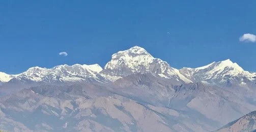 "Autumn panorama from Poon Hill featuring the snow-covered Annapurna and Dhaulagiri mountain ranges beneath a crystal-clear blue sky in Nepal's Annapurna Conservation Area.
