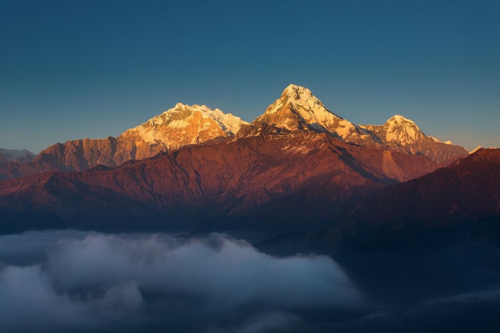 October sunrise from Poon Hill with Annapurna South and Baraha Shikhar (Fang) glowing in golden morning light above the Himalayan landscape