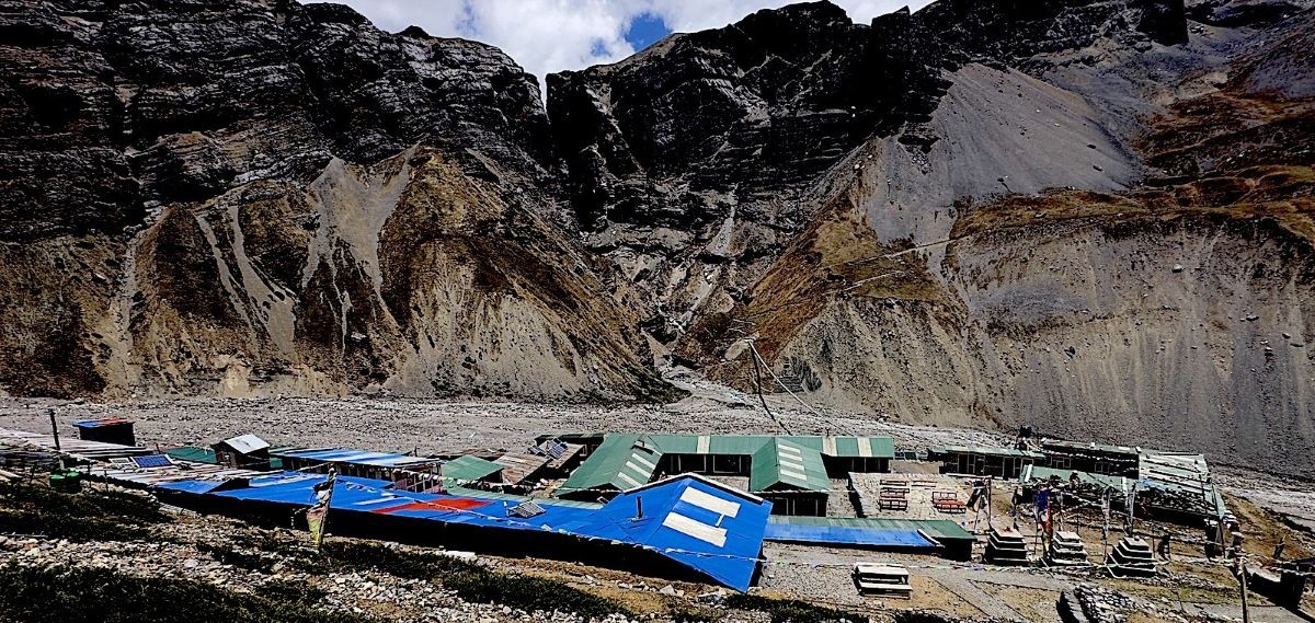 Mountain teahouses at Thorong Phedi on the Annapurna Circuit Trek sit beneath rugged cliffs under a clear September sky, illustrating a typical high-altitude stop where nights become cold despite pleasant daytime temperatures.