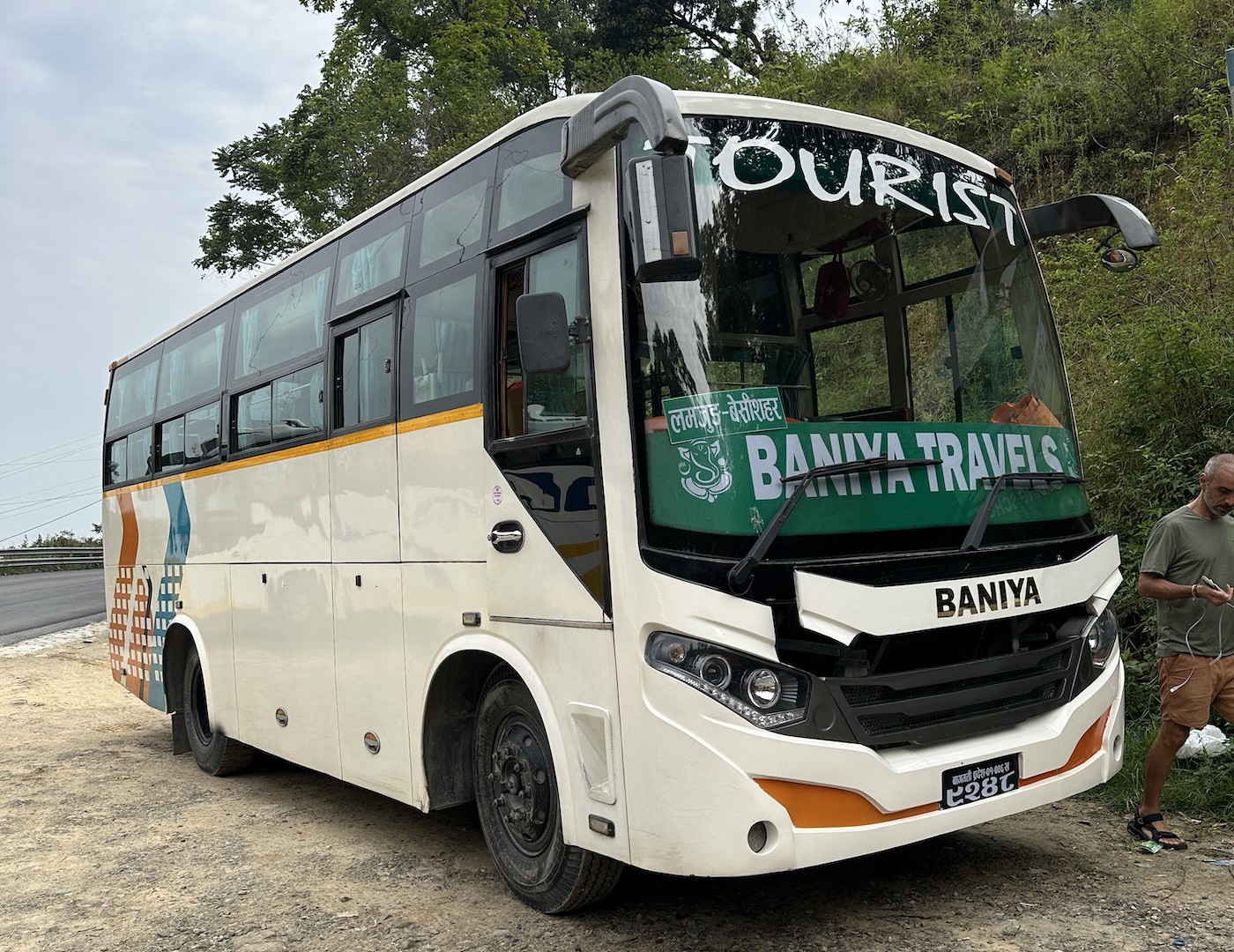 Tourist bus traveling from Kathmandu to Besisahar along a winding mountain highway in Nepal, passing rivers, terraced hills, and rural Himalayan landscapes.