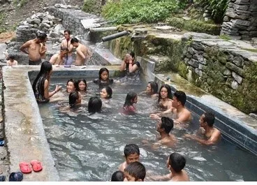 Jhinu Hot Spring beside the Modi Khola River, surrounded by lush green forests, natural stone pools, and peaceful Himalayan scenery on the Annapurna Base Camp Trek.