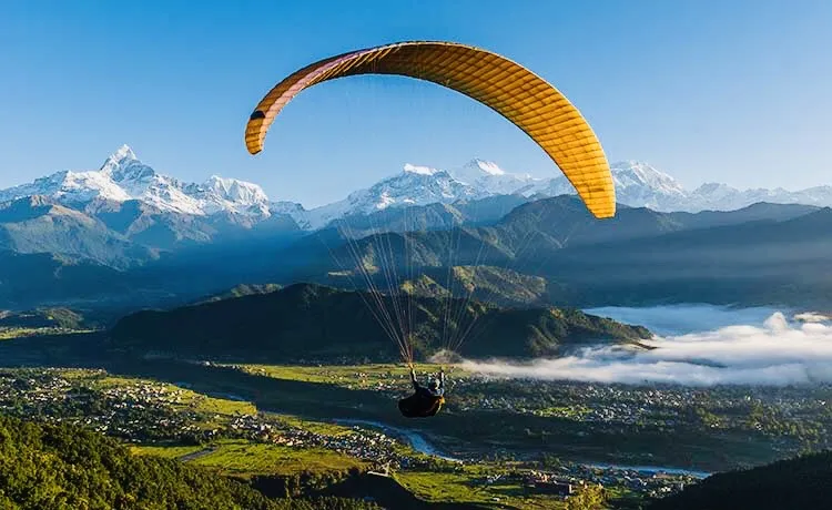 Paraglider flying above Pokhara with Phewa Lake and Himalayan mountains in Nepal.