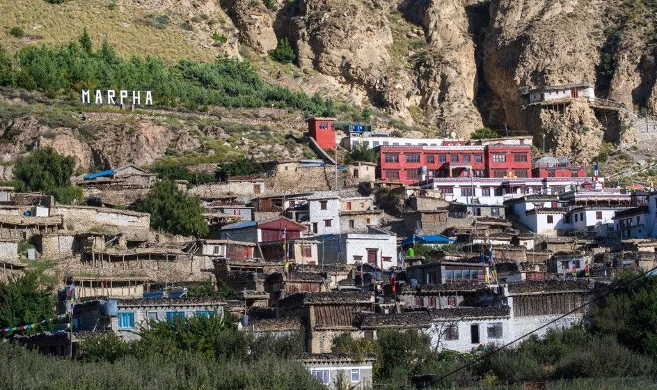 Marpha village in Mustang Nepal with traditional whitewashed houses, apple orchards, and Himalayan mountain backdrop”