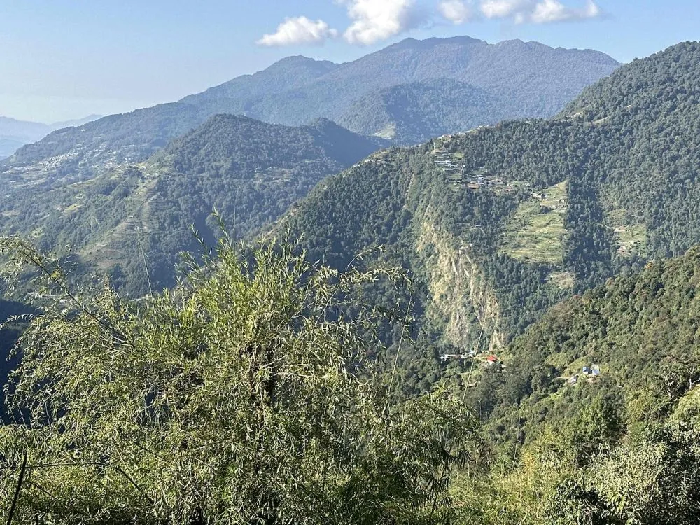 Panoramic view from the trail between Sinuwa and Jhinu Danda showing deep valleys, traditional mountain villages, terraced hillsides, forests, and scenic Annapurna foothill landscapes.