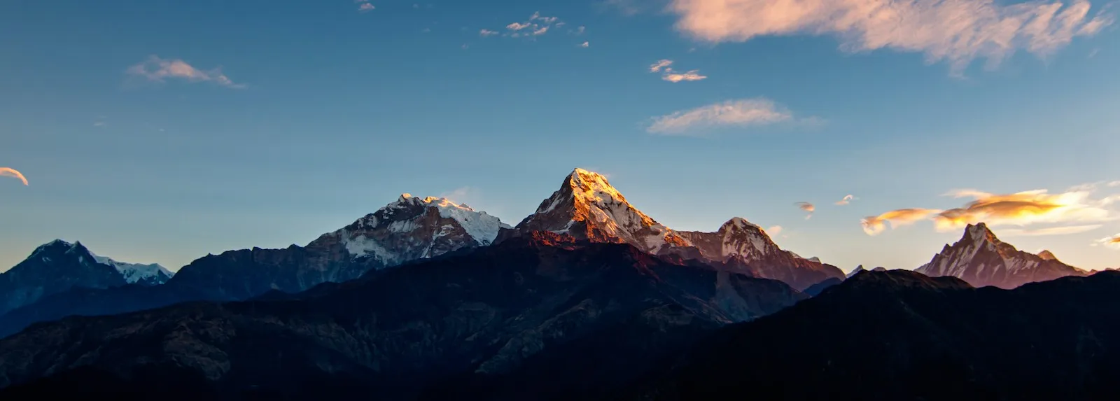 Sunrise at Poon Hill in November with trekkers watching golden sunlight illuminate the Annapurna and Dhaulagiri mountain ranges under clear, cold Himalayan skies.