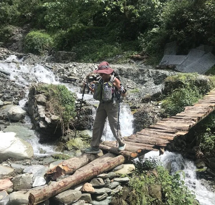 Temporary wooden bridge across a stream on a Nepal trekking trail during the monsoon season.