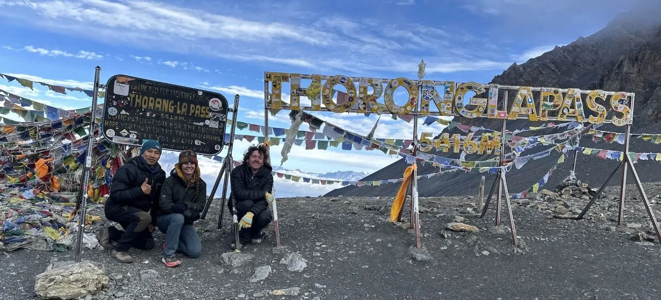 Thorong La Pass on the Annapurna Circuit Trek with colorful prayer flags and clear Himalayan views in September, Nepal.