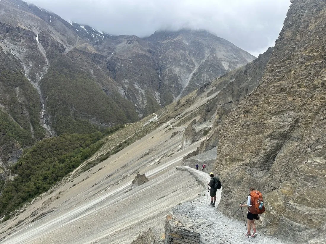 tilicho lake base camp trail: Rocky and slippery trekking trail leading to Tilicho Base Camp in Nepal, with loose stones, steep terrain, and dramatic Himalayan mountain surroundings.