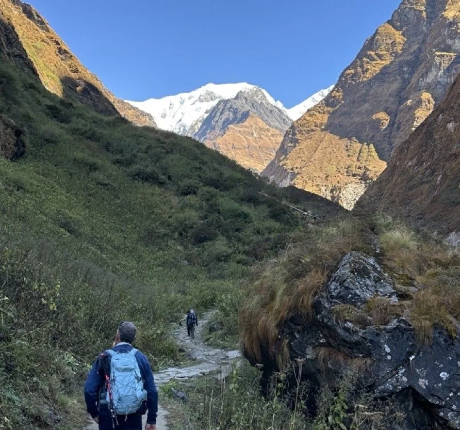 Trekkers heading toward Machhapuchhre Base Camp (MBC) along a scenic alpine trail, surrounded by glacial valleys, rugged mountain terrain, and spectacular views of Machhapuchhre (Fishtail Mountain).