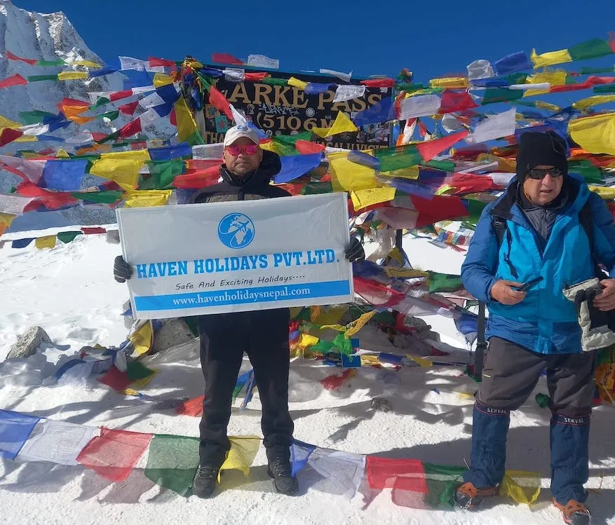 Trekkers at Larke Pass with colorful prayer flags in the Manaslu region.