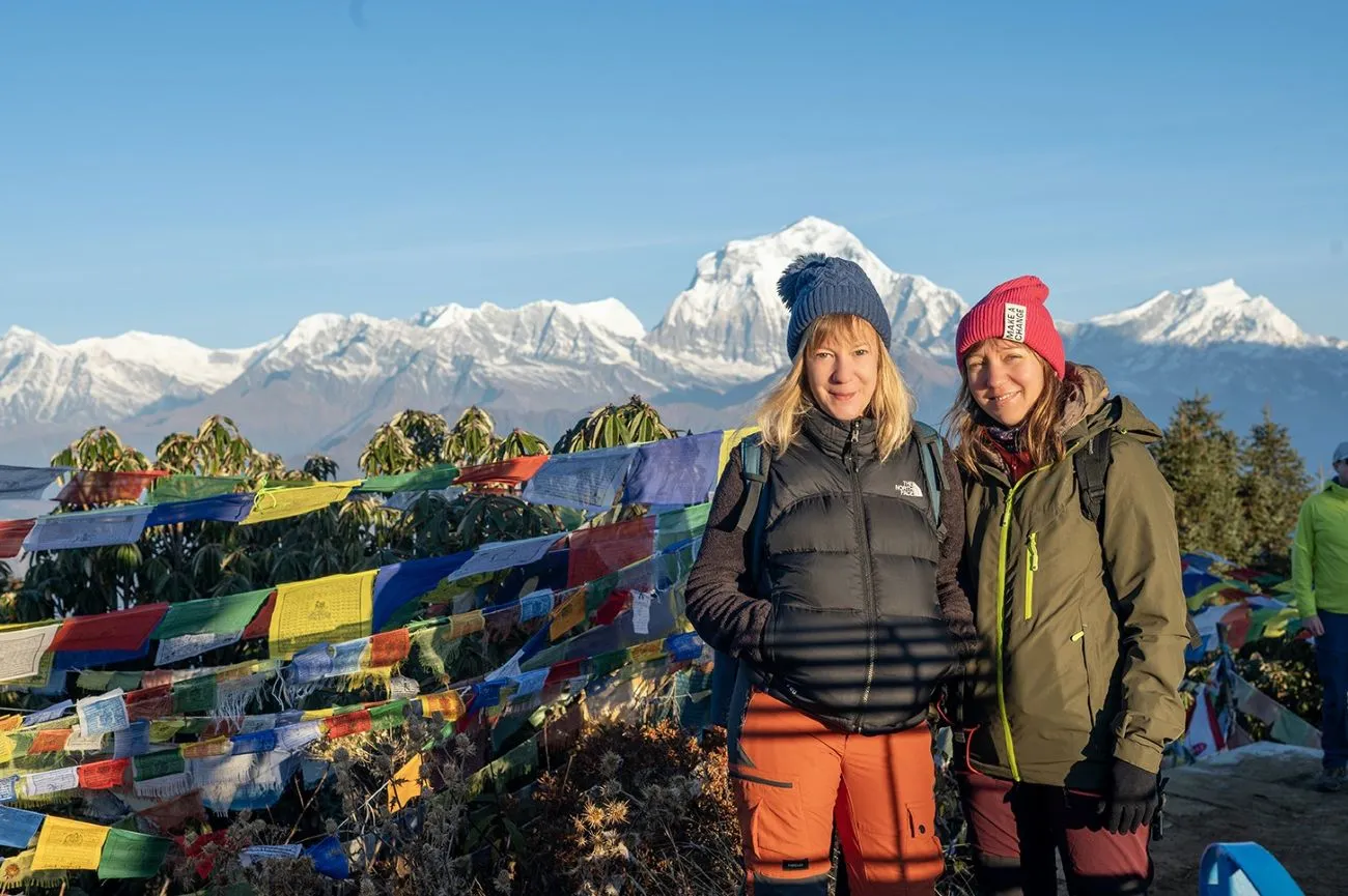 Trekkers hiking to Poon Hill before sunrise wearing warm down jackets, beanies, gloves, neck gaiters, trekking boots, and headlamps under a star-filled Himalayan sky.